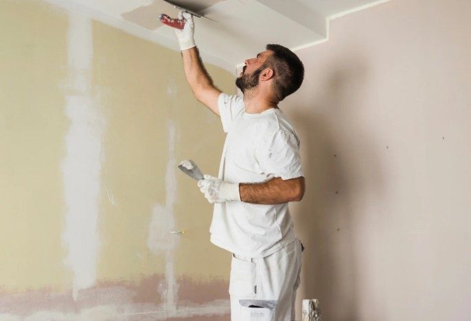 Pintor alisando con espátula el encuentro de techo y pared tras eliminar el gotelé en un piso de Vigo